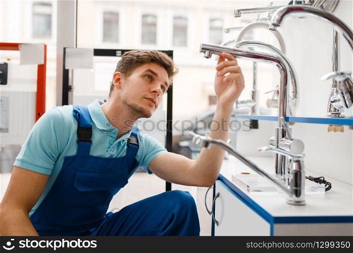 Plumber in uniform at showcase in plumbering store. Man with notebook buying sanitary engineering in shop, water taps and faucets choice. Plumber in uniform at showcase in plumbering store