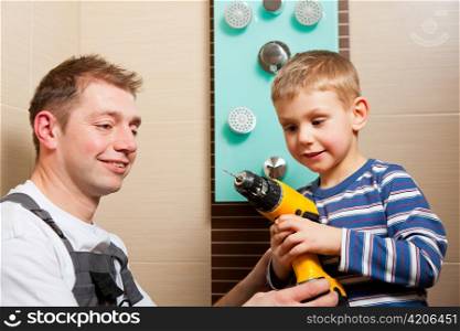 Plumber installing a mixer tap in a bathroom; he explains it to his son