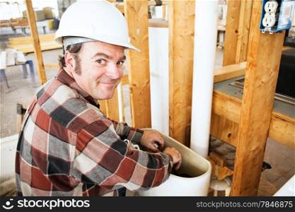 Plumber installing a toilet in a home which is under construction.