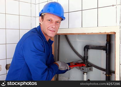 Plumber installing pipes with a large wrench