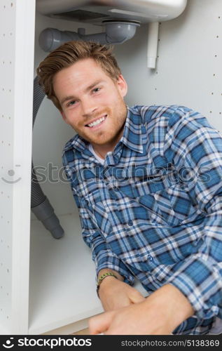 plumber posing under the sink