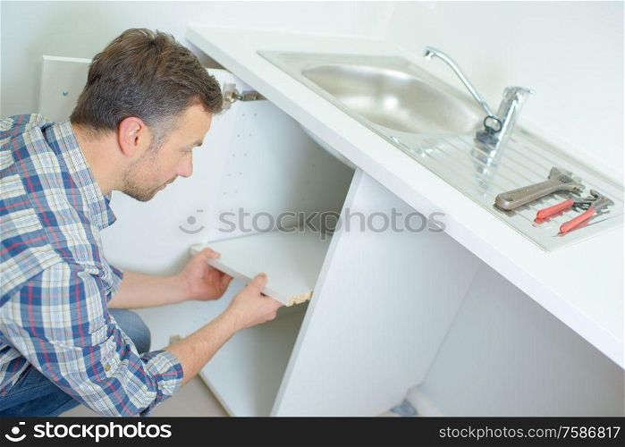 plumber removing the shelf under the sink