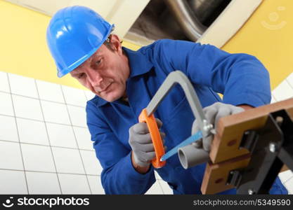 Plumber sawing a pipe