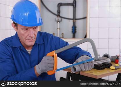 Plumber sawing plastic pipe