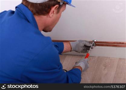 Plumber securing pipe to wall