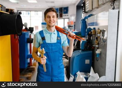 Plumber shows pipe wrenches at the showcase in plumbering store. Man buying sanitary engineering tools and equipment in shop. Plumber shows pipe wrenches in plumbering store