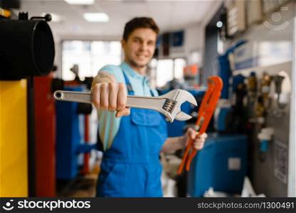 Plumber shows pipe wrenches at the showcase in plumbering store. Man buying sanitary engineering tools and equipment in shop. Plumber shows pipe wrenches in plumbering store