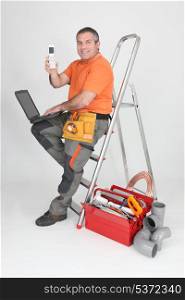 plumber sitting on stepladder showing phone
