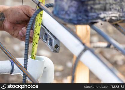 Plumber Using Level And Tape Measure While Installing PVC Pipe At Construction Site.