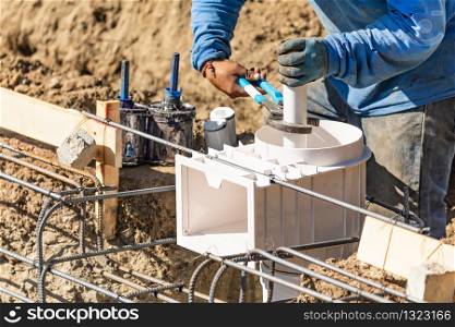 Plumber Using Wrench to Install PVC Pipe at Construction Site.