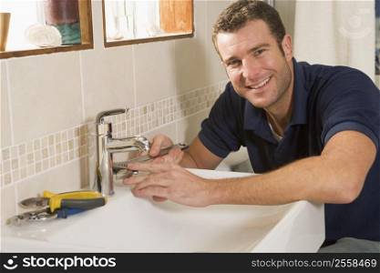 Plumber working on sink smiling