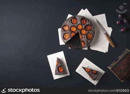 Plums dessert with chocolate and two slices on old books pages. Above view with autumn sweet food. Relaxing time frame. Flat lay with copy space.
