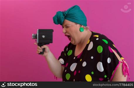 plus size smiling woman with funny emotional face expression with vintage camera in dress isolated on pink background, traveler on vacation, summer fashion style, excited tourist. High quality photo. plus size smiling woman with funny emotional face expression with vintage camera in dress isolated on pink background, traveler on vacation, summer fashion style, excited tourist.