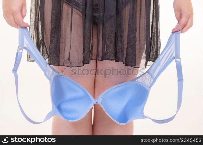 Plus size woman wearing lingerie holding ful cup bra, on white. Bosom, brafitting, underwear and female dilemmas.. Woman plus size holding bra