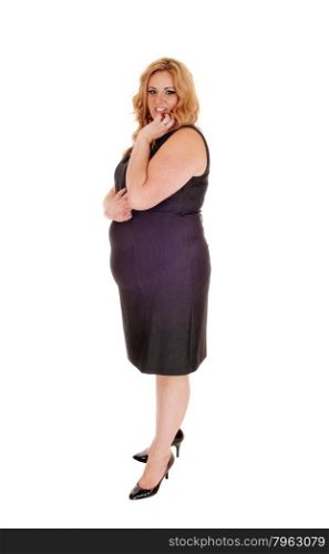 Plus size young woman standing isolated for white background withher hand on her chin, in high heels and a gray dress.