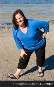 Plus sized woman stretching on the beach as part of fitness program.