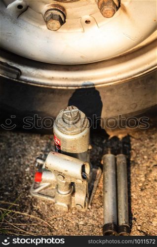 Pneumatic car jack next to old tire. Auto mobile repair objects concept.. Pneumatic car jack next to old tire