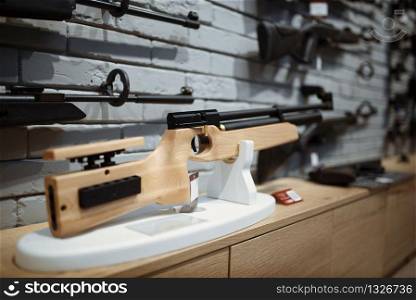 Pneumatic rifles on showcase in gun shop closeup, nobody. Euqipment for hunters on stand in weapon store, hunting and sport shooting hobby. Pneumatic rifles on showcase in gun shop closeup