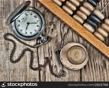 pocket watch, abacus and stamp on a wooden table