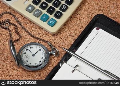 pocket watch and calculator on a cork board