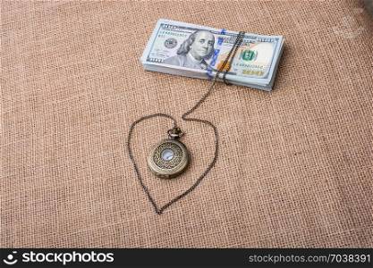 Pocket watch wrapped around bundle of US dollar forms a heart