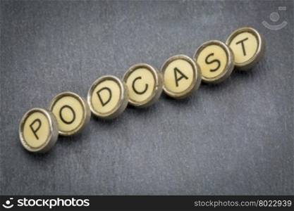 podcast word in old round typewriter keys against gray slate stone
