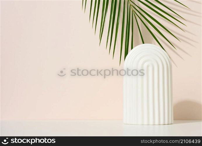 podium with white arches to showcase cosmetics, products and other merchandise. Green palm leaf