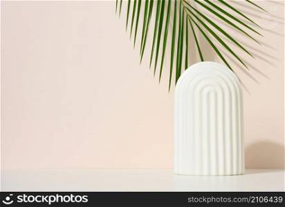 podium with white arches to showcase cosmetics, products and other merchandise. Green palm leaf