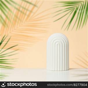 Podium with white arches to showcase cosmetics, products and other merchandise. Green palm leaf