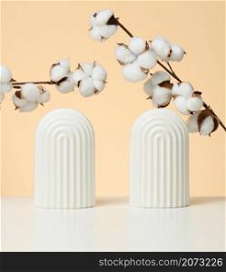 podium with white flower cotton and arches to showcase cosmetics, products and other goods, beige background