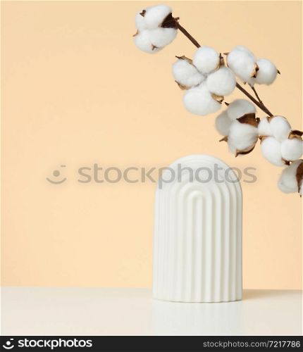 podium with white flower cotton and arches to showcase cosmetics, products and other goods, beige background