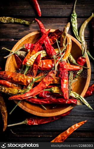 Pods of dried chili peppers in a plate. On a wooden background. High quality photo. Pods of dried chili peppers in a plate.