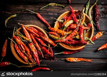 Pods of dried chili peppers in a plate. On a wooden background. High quality photo. Pods of dried chili peppers in a plate.