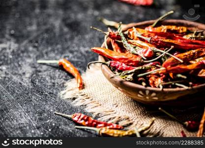 Pods of dried chili peppers in a wooden plate on a napkin. On a black background. High quality photo. Pods of dried chili peppers in a wooden plate on a napkin.
