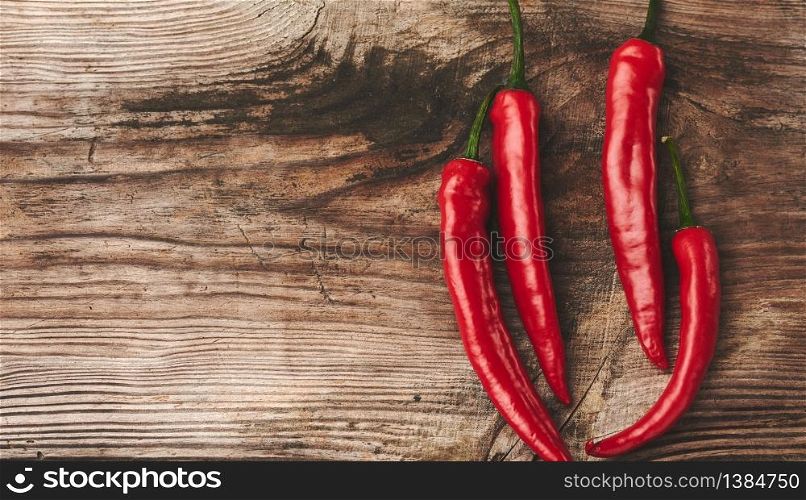 pods of red chili peppers on a gray wooden board, top view, copy space