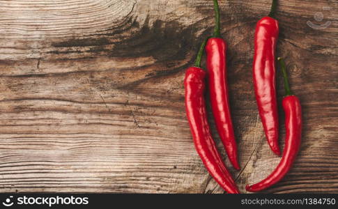 pods of red chili peppers on a gray wooden board, top view, copy space