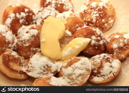 Poffertjes, Dutch small, fluffy pancakes, served with powdered sugar and butter.