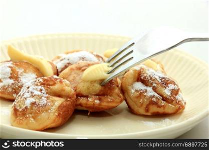 Poffertjes, Dutch small, fluffy pancakes, served with powdered sugar and butter.