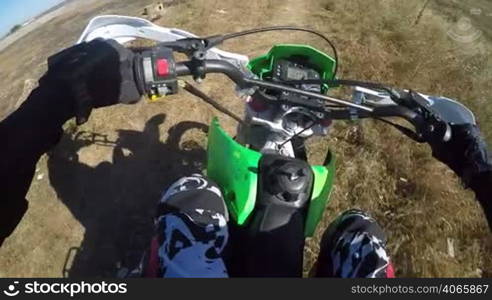 Point of View: Enduro rider riding motorcycle on dirt track