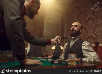 Poker player grabbed his opponent&rsquo;s tie, sharper in casino, risk. Games of chance addiction. Men with whiskey and cigars in gambling house