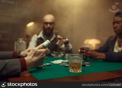Poker player holds roll of money, casino. Games of chance addiction, risk, gambling house. Men leisures with whiskey and cigars