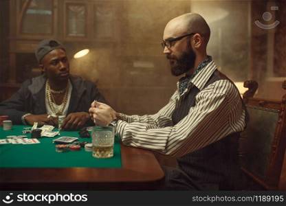 Poker players place money bets on gaming table with green cloth in casino. Games of chance addiction, risk, gambling house. Men leisures with whiskey and cigars. Poker players place money bets on gaming table