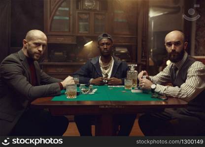 Poker players with cards playing in casino. Games of chance addiction, gambling house. Men leisures with whiskey and cigars. Poker players with cards playing in casino
