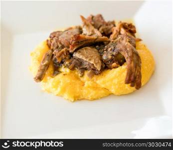 Polenta with small goat roast. Typical italian food,polenta with Capretto( small goat meat) roasted, close up.