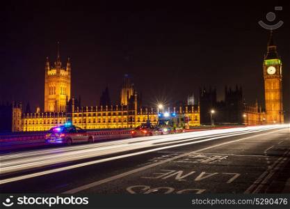 Police Cars and Ambulance on Westminster Bridge, London at Night with The Houses of Parliament and Big Ben