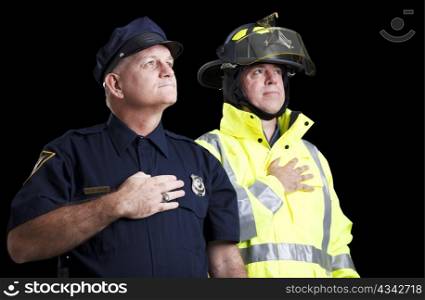 Police officer and fire fighter with their hands over their hearts as they say the Pledge of Allegiance.