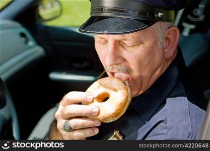 Police officer biting into a delicious glazed donut.