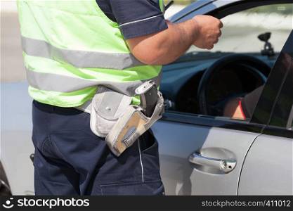 Police officer checking driving license of a car driver during traffic control