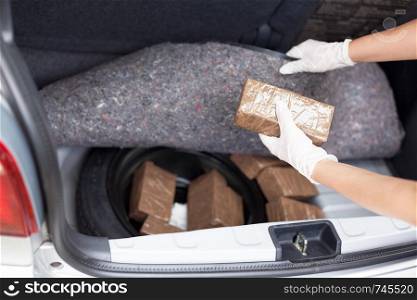 Police officer holding drug package discovered in the trunk of a car
