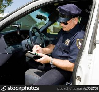 Police officer in his squad car, filling out a citation.